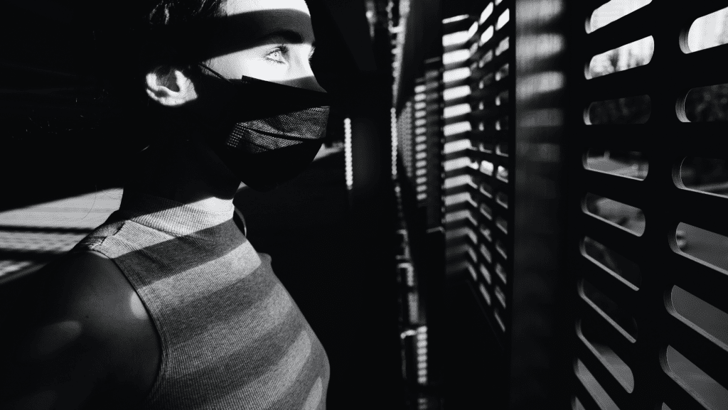 person in mask looking out window